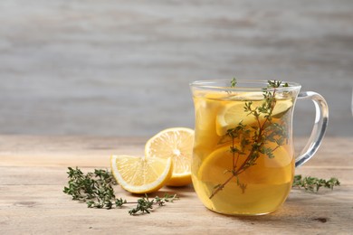 Aromatic herbal tea with thyme and lemon on wooden table, space for text