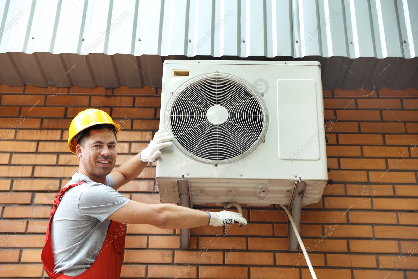 Photo of Male technician fixing air conditioner outdoors