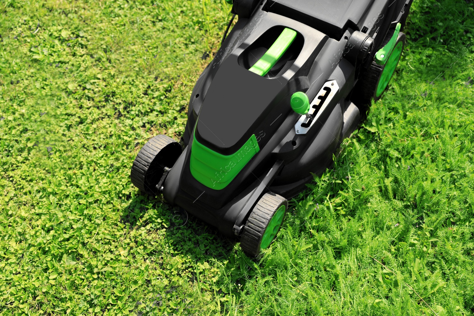 Photo of Cutting green grass with lawn mower in garden, above view