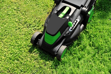 Cutting green grass with lawn mower in garden, above view