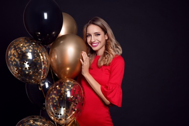 Happy woman with air balloons on black background, space for text. Christmas party