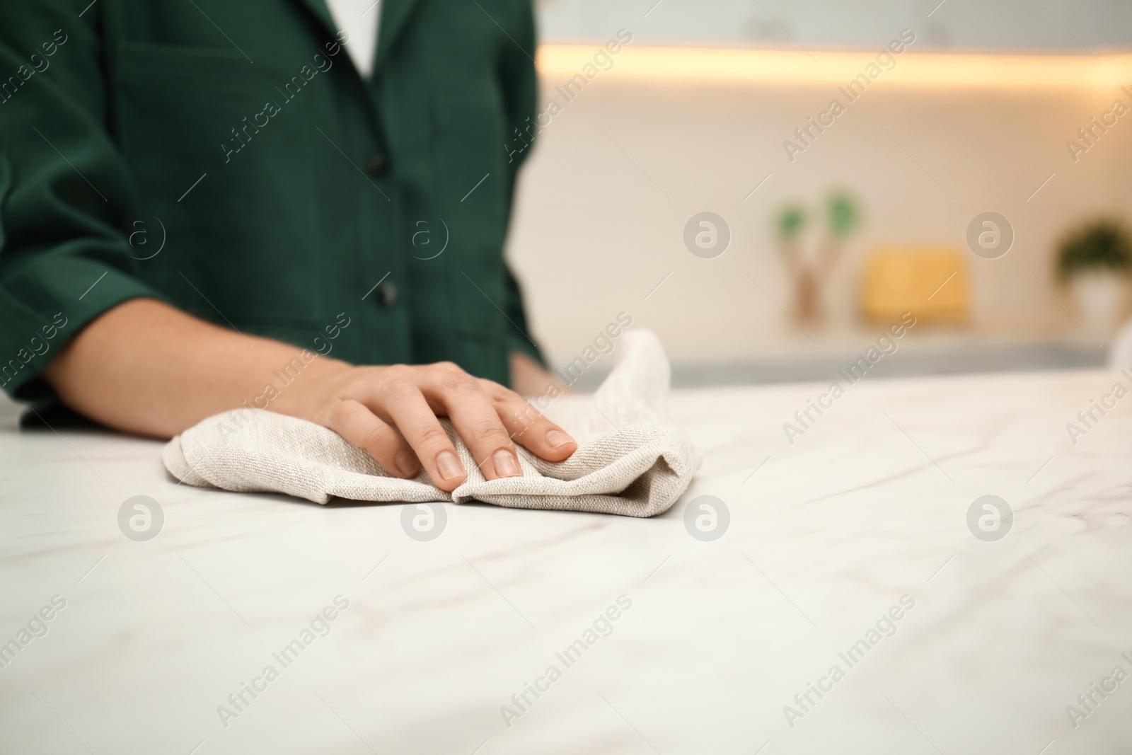 Photo of Woman wiping white table with towel in kitchen