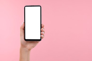 Photo of Woman holding smartphone with blank screen on pale pink background, closeup. Mockup for design