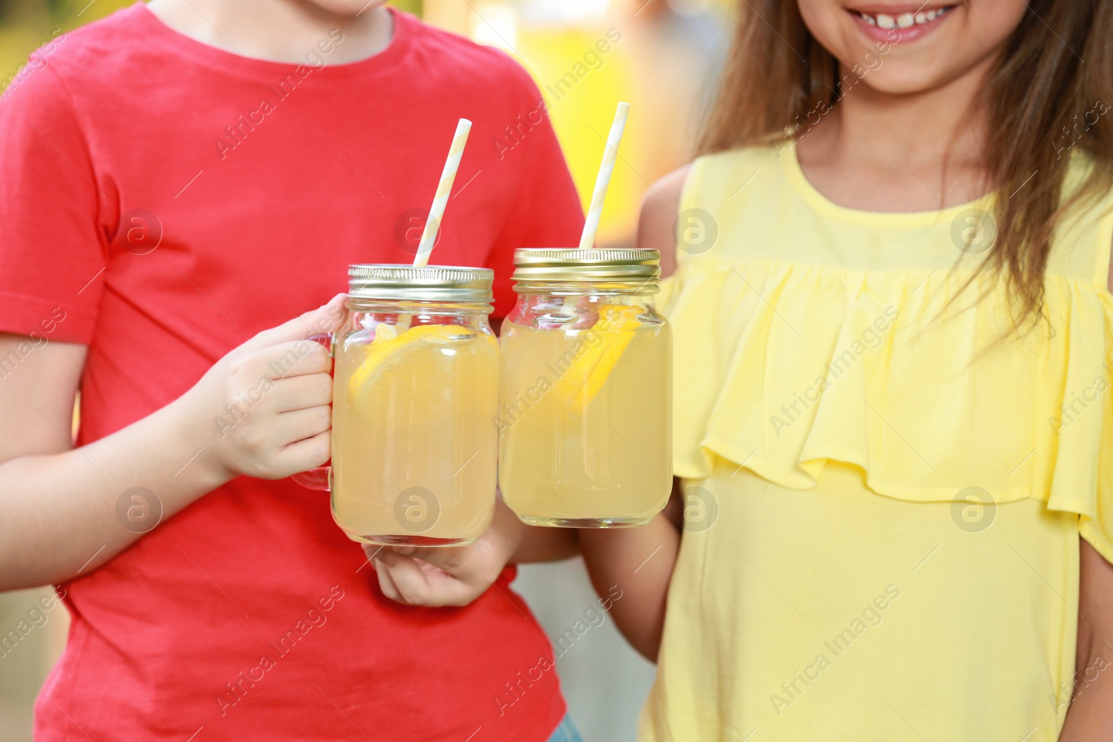 Photo of Little girls with natural lemonade, closeup. Summer refreshing drink