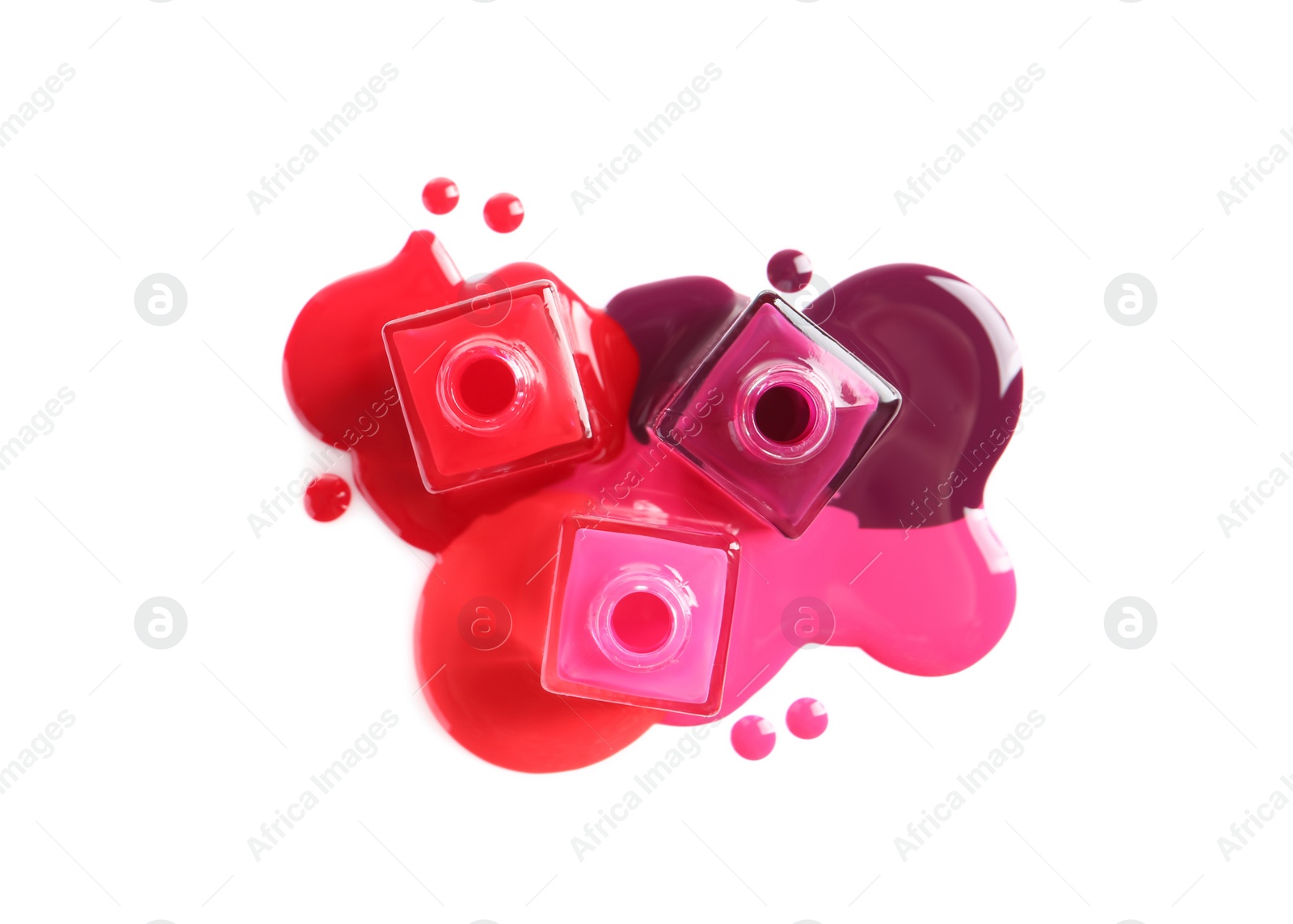 Photo of Spilled different nail polishes with bottles on white background, top view