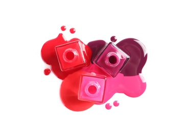 Photo of Spilled different nail polishes with bottles on white background, top view