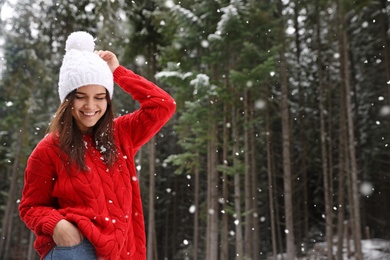 Young woman in warm sweater outdoors on snowy day, space for text. Winter vacation