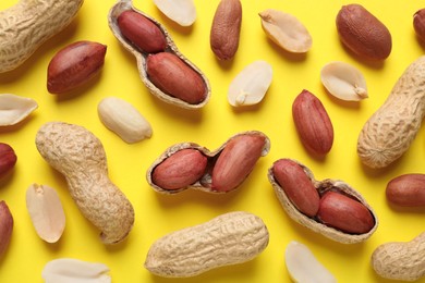 Fresh peanuts on yellow background, flat lay