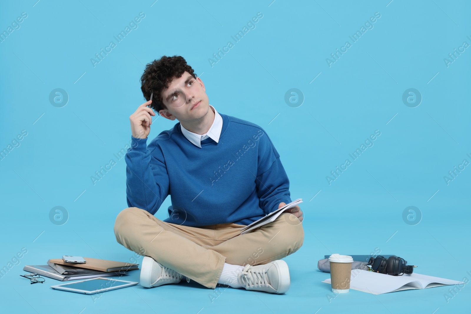 Photo of Portrait of student with notebook and stationery on light blue background