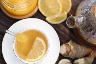 Photo of Cup of delicious tea with lemon and honey on wooden table, flat lay