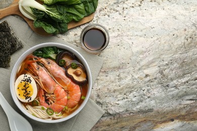 Photo of Delicious ramen with shrimps and egg in bowl served on grey textured table, flat lay with space for text. Noodle soup