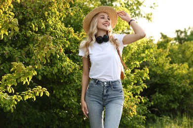 Happy young woman with headphones in park on spring day