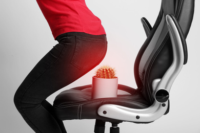 Hemorrhoid concept. Woman sitting down into armchair with cactus on white background, closeup