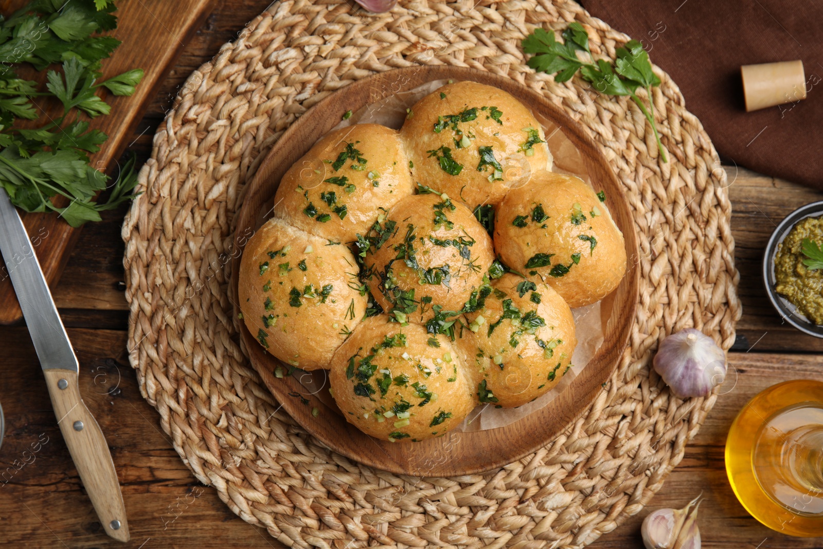 Photo of Traditional pampushka buns with garlic and herbs on wooden table, flat lay