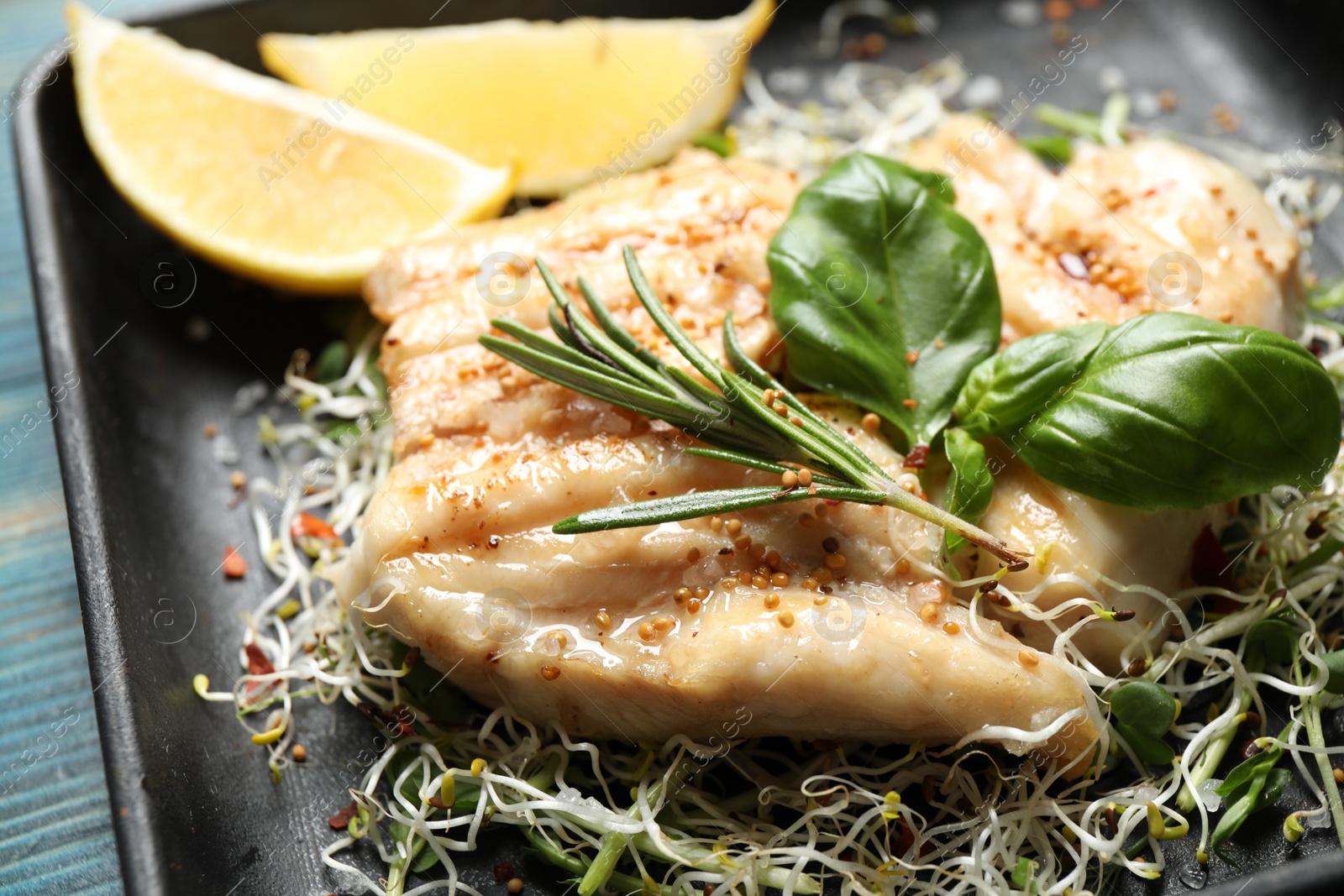 Photo of Tasty grilled fish with herbs in baking dish, closeup