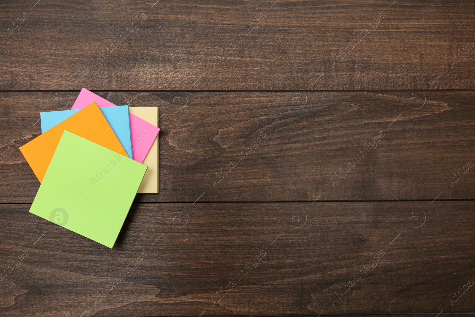 Photo of Stack of colorful stickers on wooden table, top view. Space for text