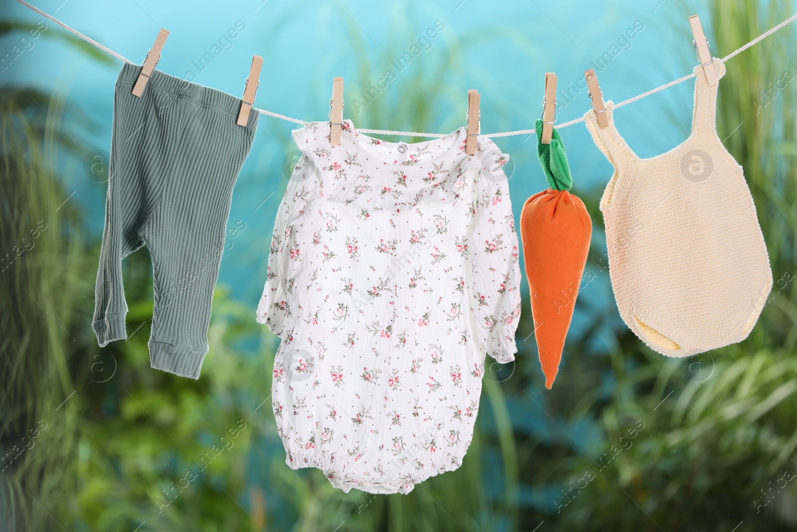 Photo of Baby clothes and carrot toy drying on laundry line outdoors