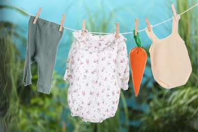 Photo of Baby clothes and carrot toy drying on laundry line outdoors