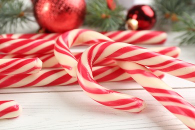 Photo of Many sweet candy canes and Christmas decor on white wooden table, closeup