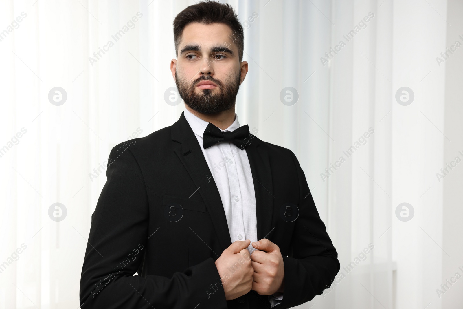 Photo of Portrait of handsome man in suit, shirt and bow tie indoors