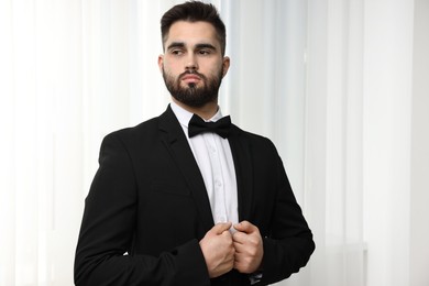 Portrait of handsome man in suit, shirt and bow tie indoors