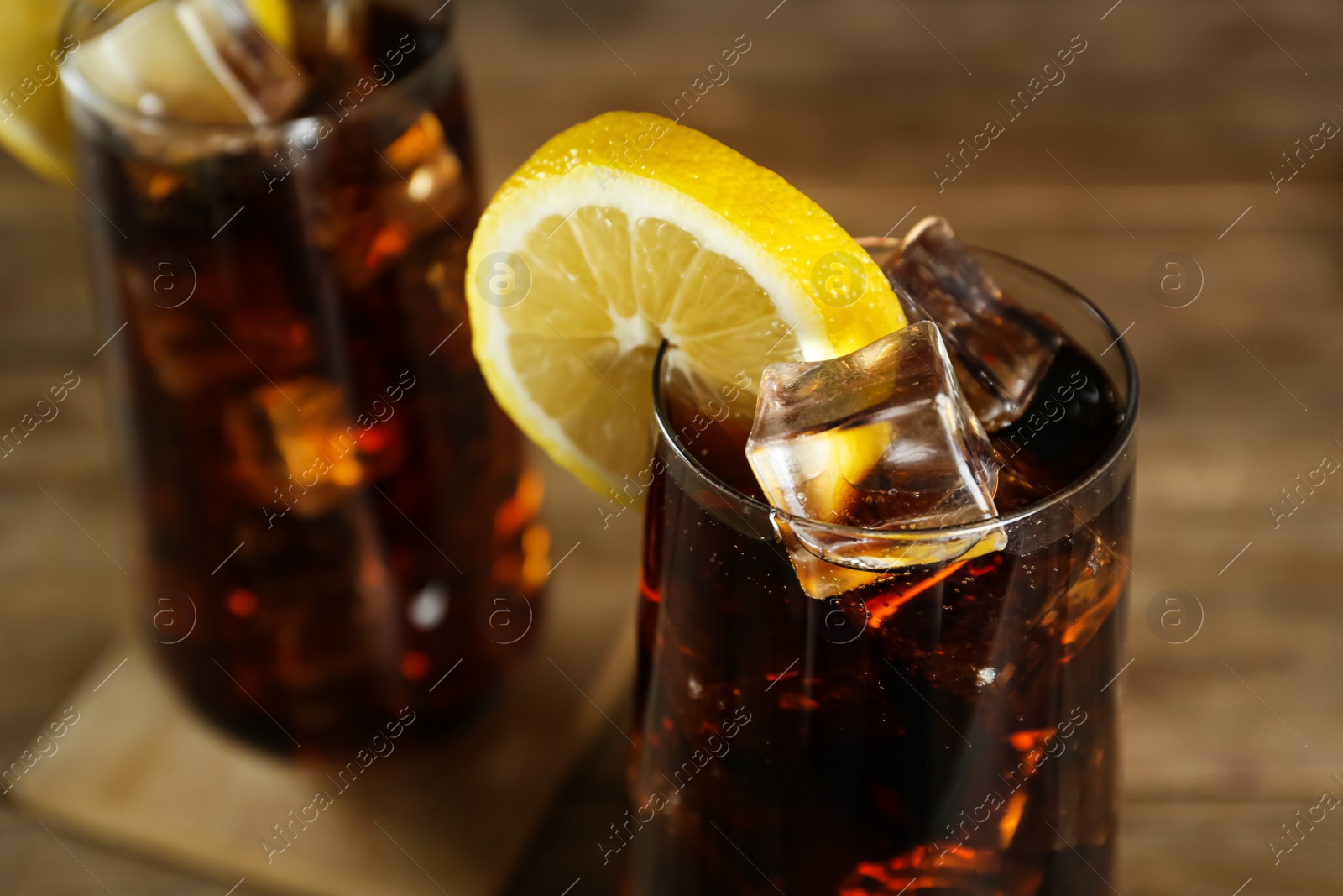 Photo of Glasses of refreshing soda water with ice cubes and lemon slices on table, closeup