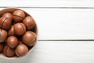 Photo of Delicious Macadamia nuts on white wooden table, top view. Space for text