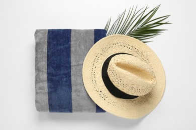 Beach towel and straw hat on white background, top view