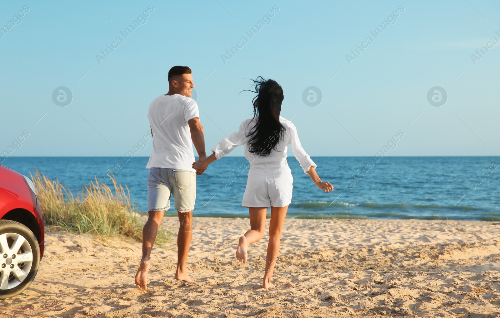 Photo of Lovely couple running on sandy beach. Summer trip