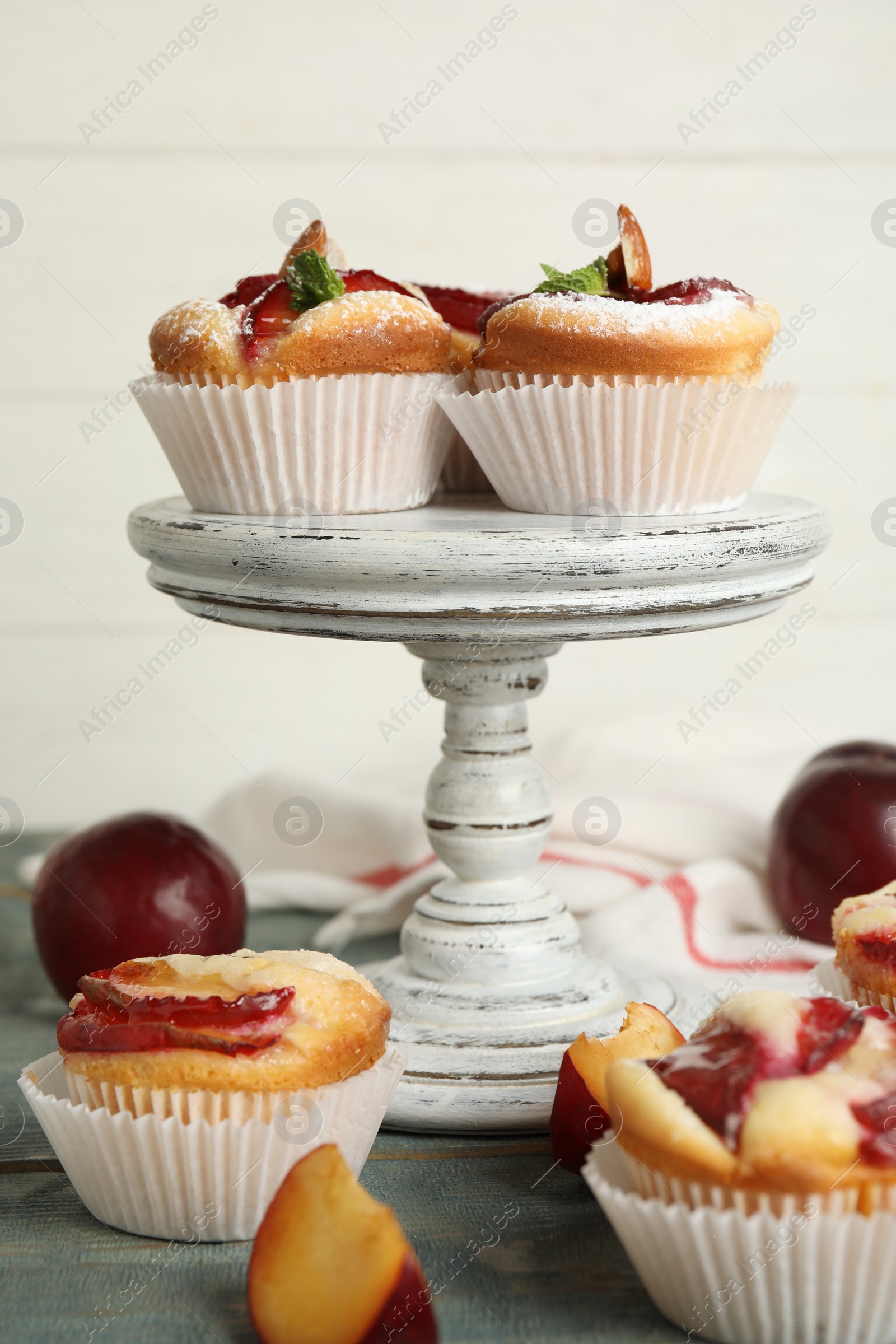 Photo of Delicious sweet cupcakes with plums on wooden table