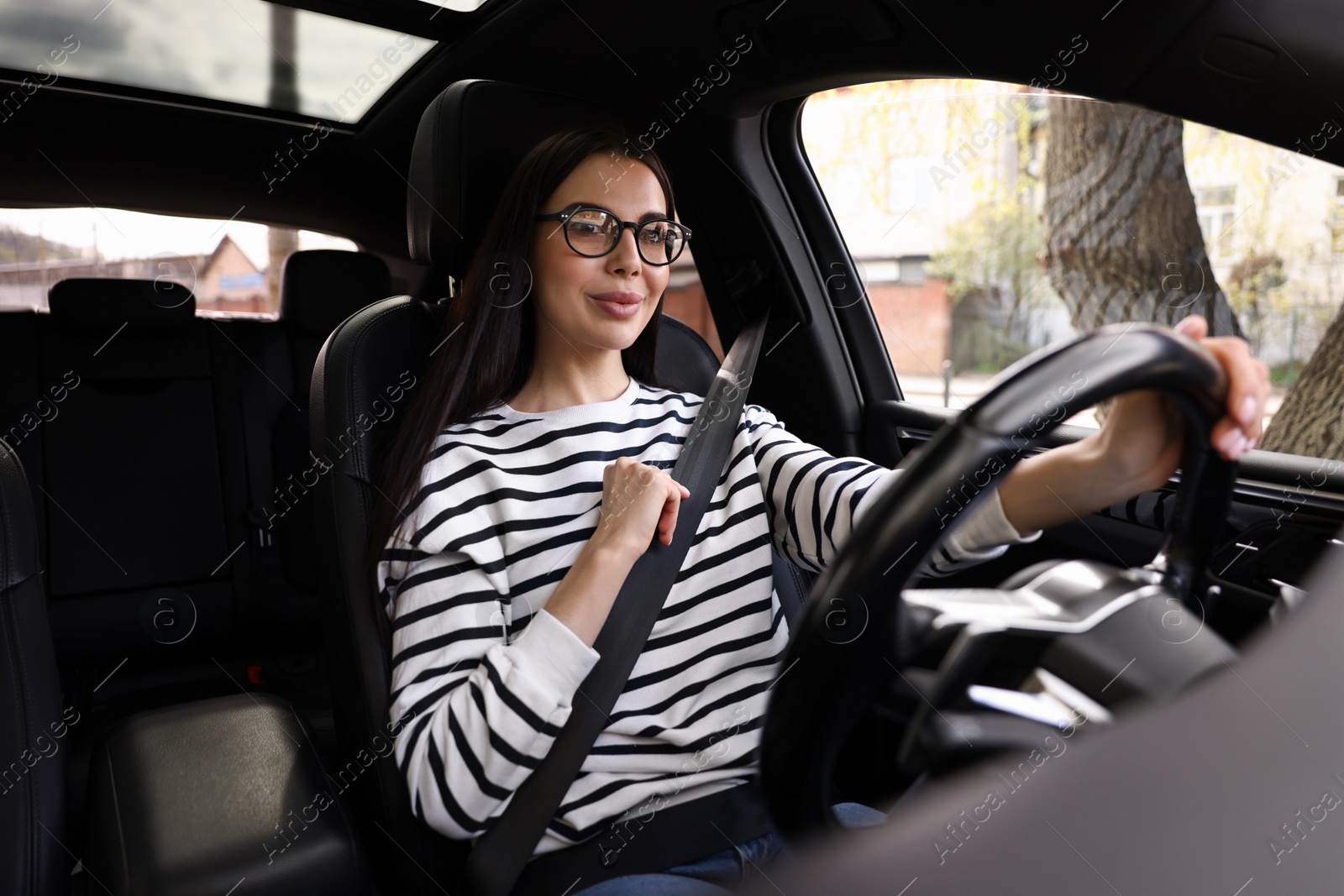 Photo of Woman with safety seat belt driving her modern car