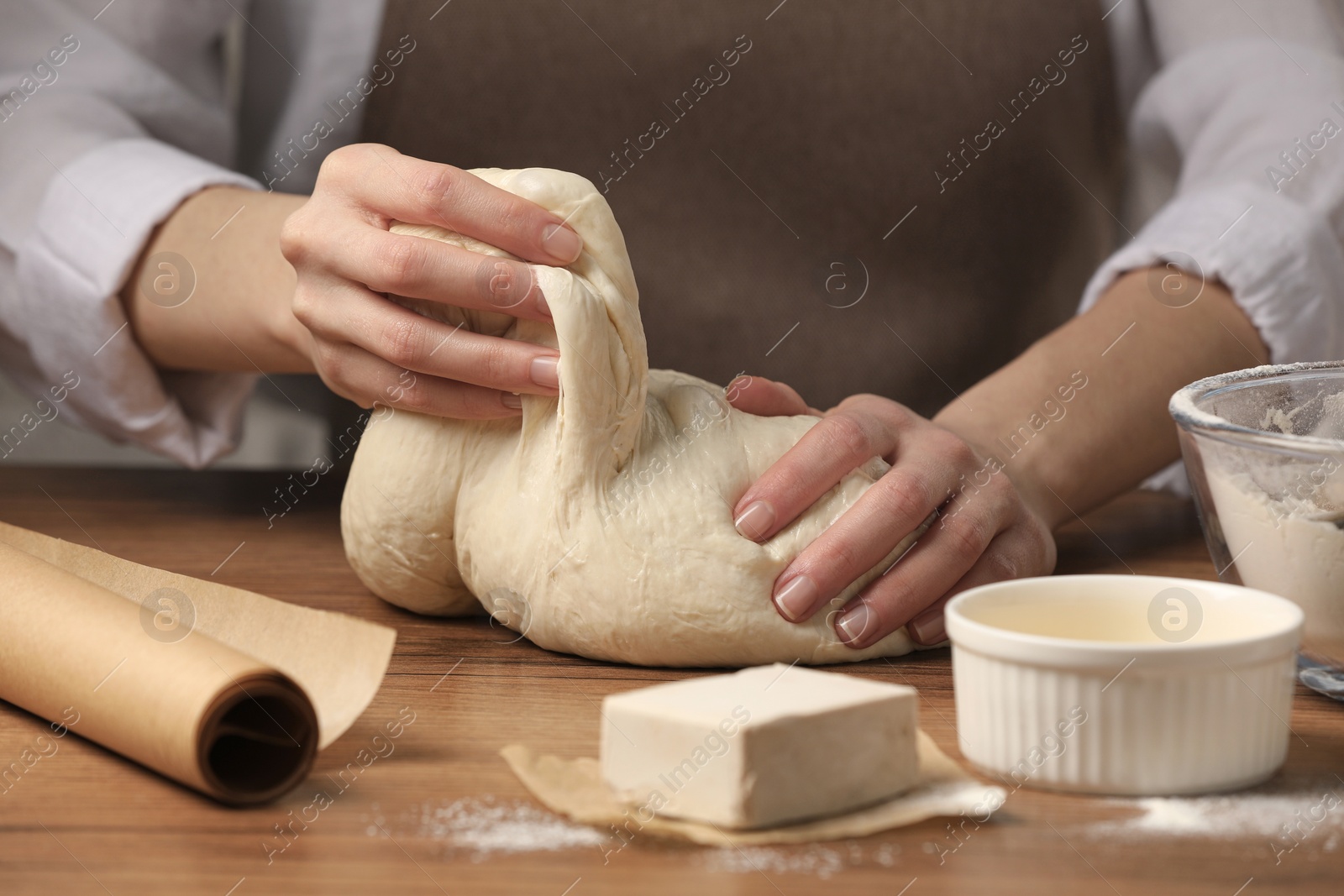 Photo of Woman kneading yeast dough for cake at wooden table, closeup