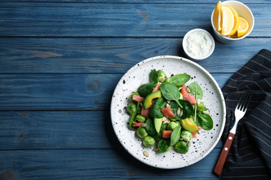 Photo of Tasty salad with Brussels sprouts served on blue wooden table, flat lay. Space for text