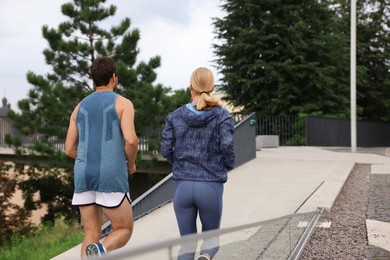 Photo of Healthy lifestyle. Sporty couple running outdoors, back view. Space for text