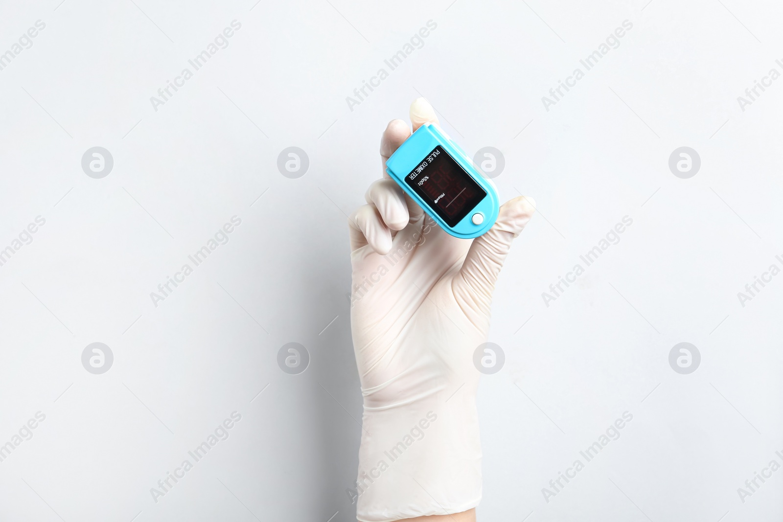 Photo of Doctor in gloves holding fingertip pulse oximeter on white background, closeup