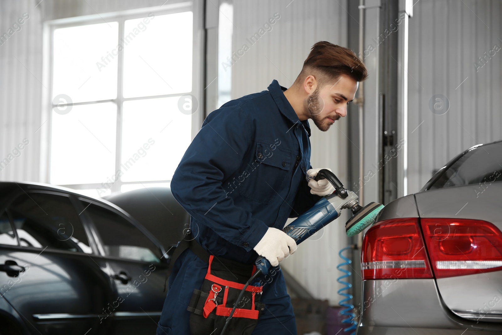 Photo of Technician polishing car body with tool at automobile repair shop