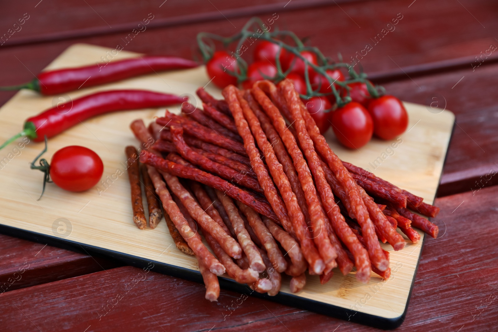 Photo of Tasty dry cured sausages (kabanosy) and ingredients on wooden table