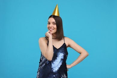 Photo of Happy young woman in party hat on light blue background