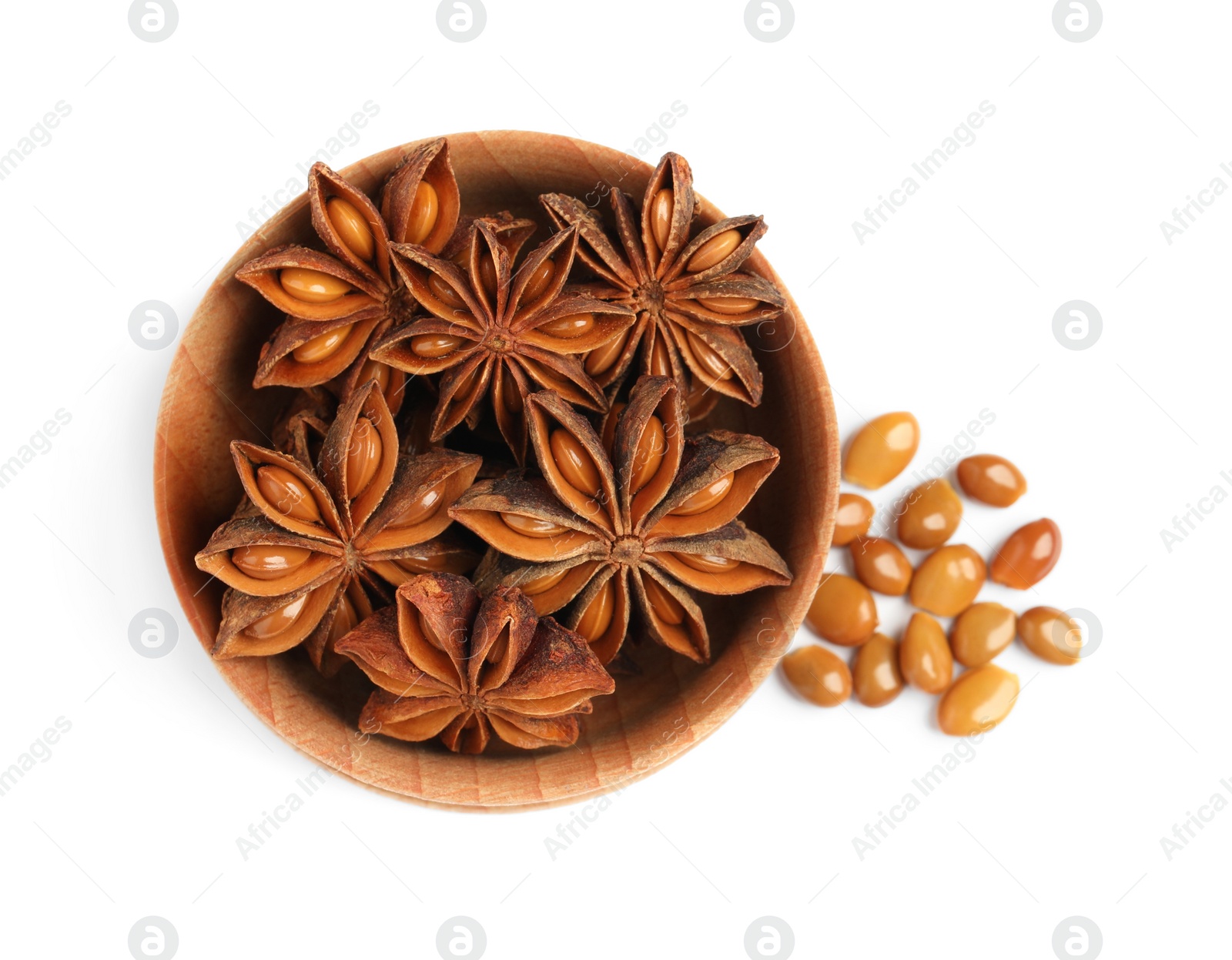 Photo of Wooden bowl with dry anise stars and seeds on white background, top view