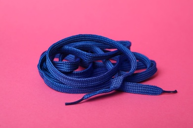 Photo of Blue shoe lace on pink background. Stylish accessory