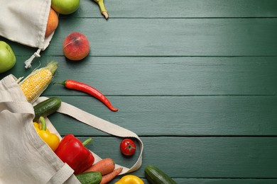 Photo of Cloth bags with fresh fruits and vegetables on green wooden table, flat lay. Space for text