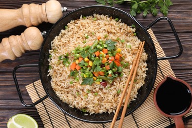 Tasty fried rice with vegetables served on wooden table, flat lay