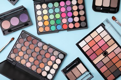 Photo of Flat lay composition with beautiful eye shadow palettes and brushes on light blue background