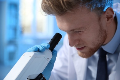 Photo of Male scientist using modern microscope in chemistry laboratory