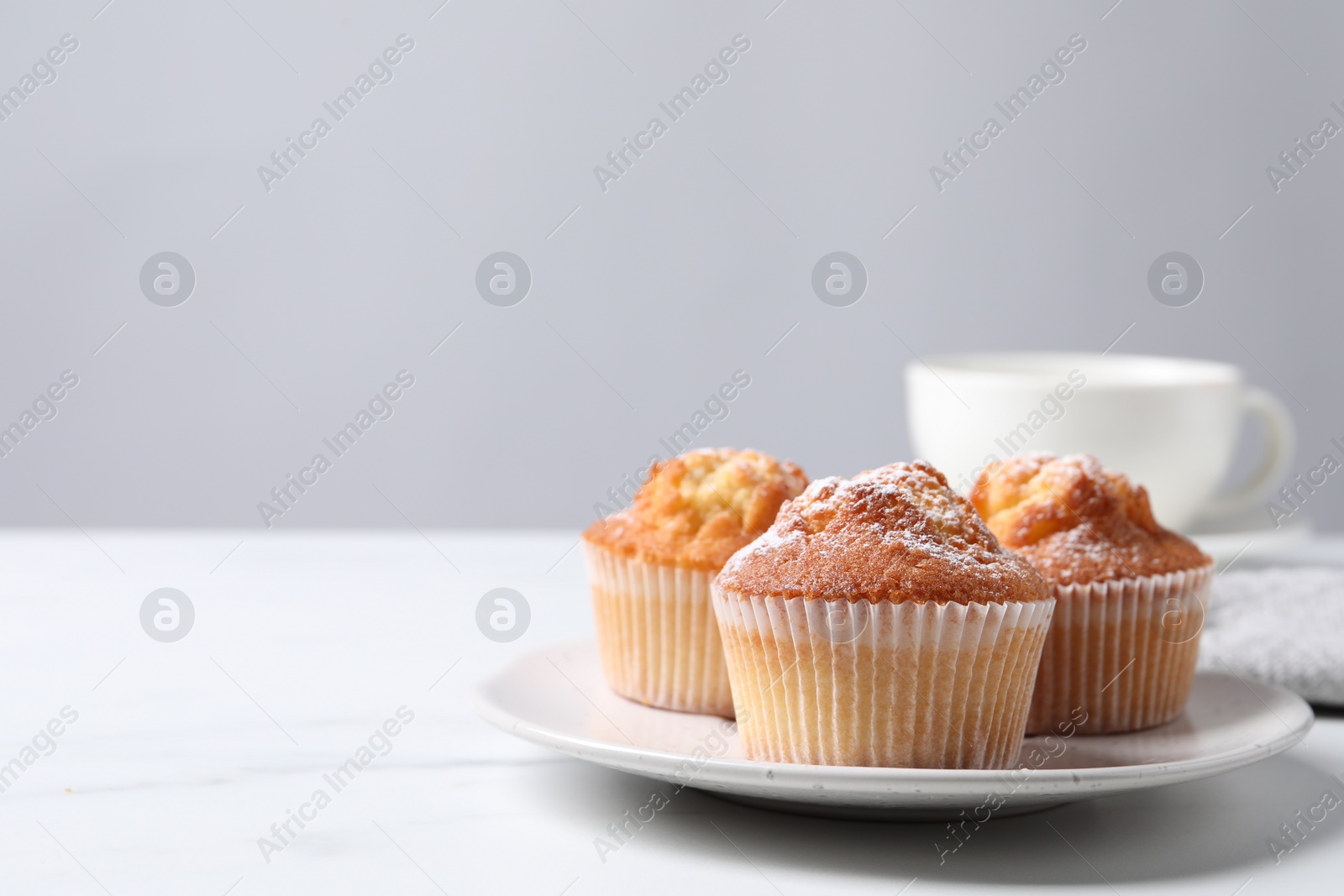 Photo of Delicious sweet muffins on white marble table against light grey background, closeup. Space for text