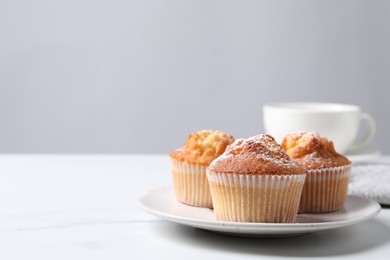 Photo of Delicious sweet muffins on white marble table against light grey background, closeup. Space for text