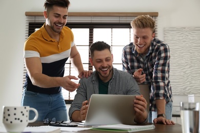Image of Happy friends working together in modern office
