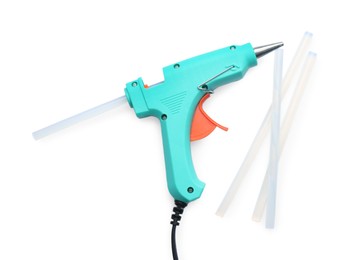 Turquoise glue gun and sticks on white background, top view