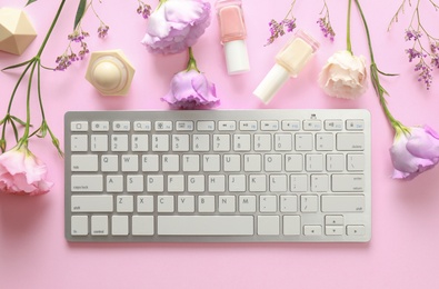 Photo of Flat lay composition with keyboard and flowers on pink background. Beauty blogger's workplace