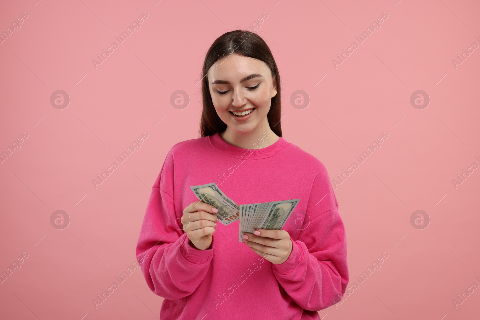 Photo of Happy woman with dollar banknotes on pink background